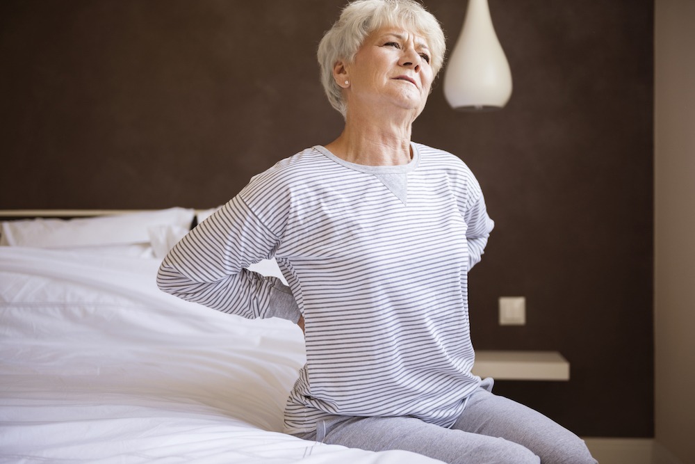 Lady with sciatica struggling to get out of bed